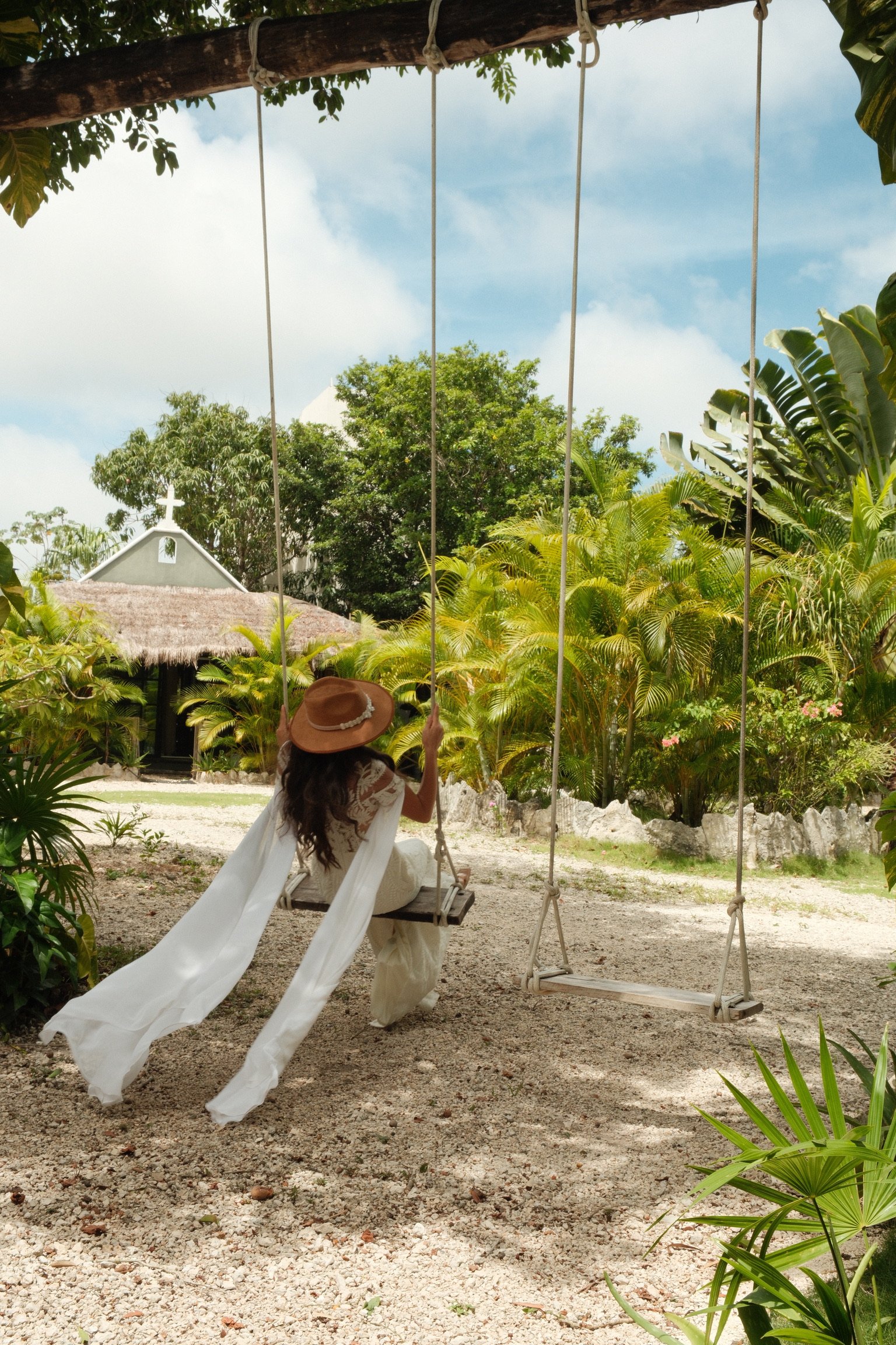 Bride on a swing with the chapel cross visible at Rancho Verde