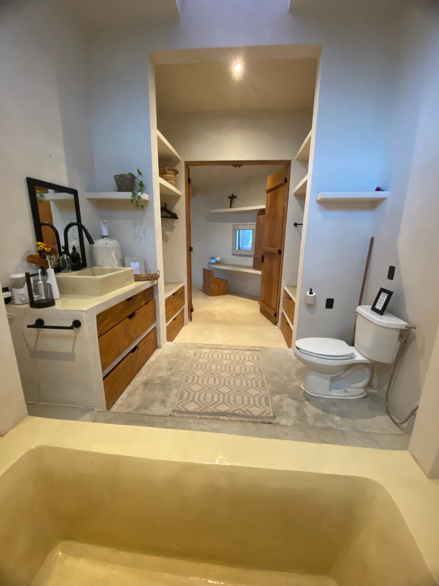 Casa Blanca bathroom with built-in concrete tub, toilet and the walk-in closet beyond, Rancho Verde Tulum, Tulum, Mexico