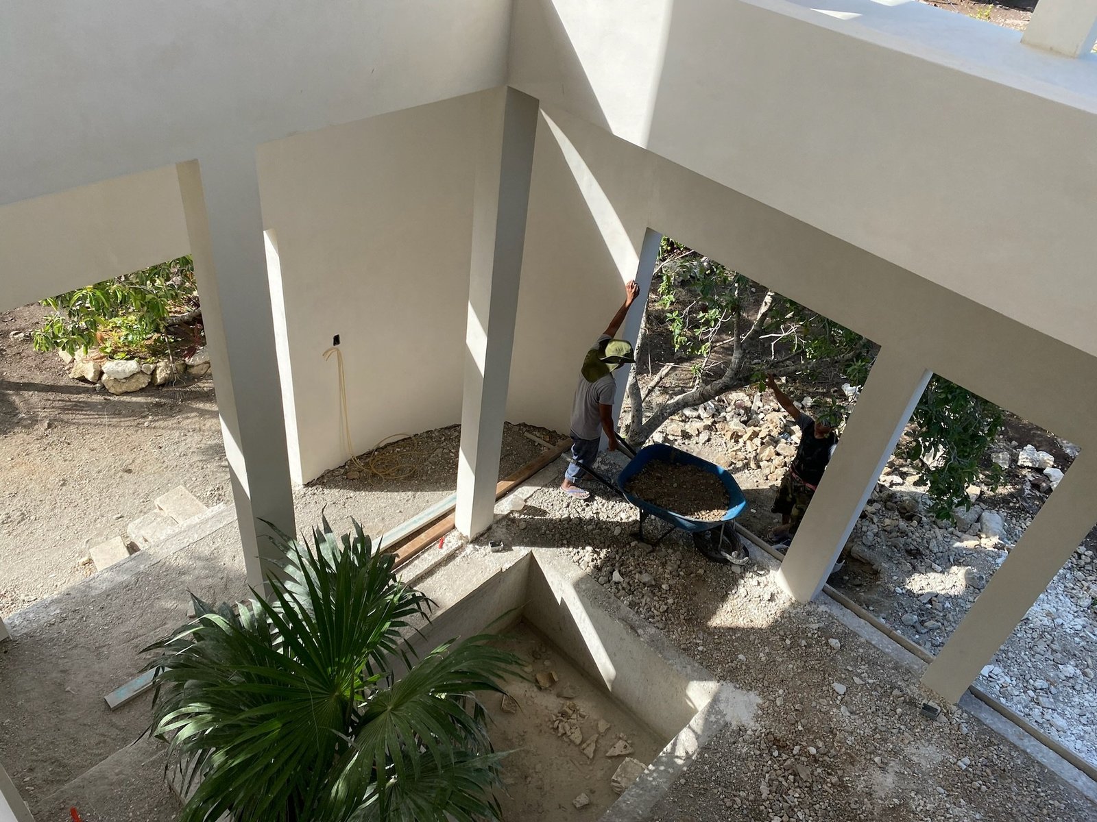 Casa Blanca white plastered courtyard with workers finishing the ground, Rancho Verde Tulum, Tulum, Mexico