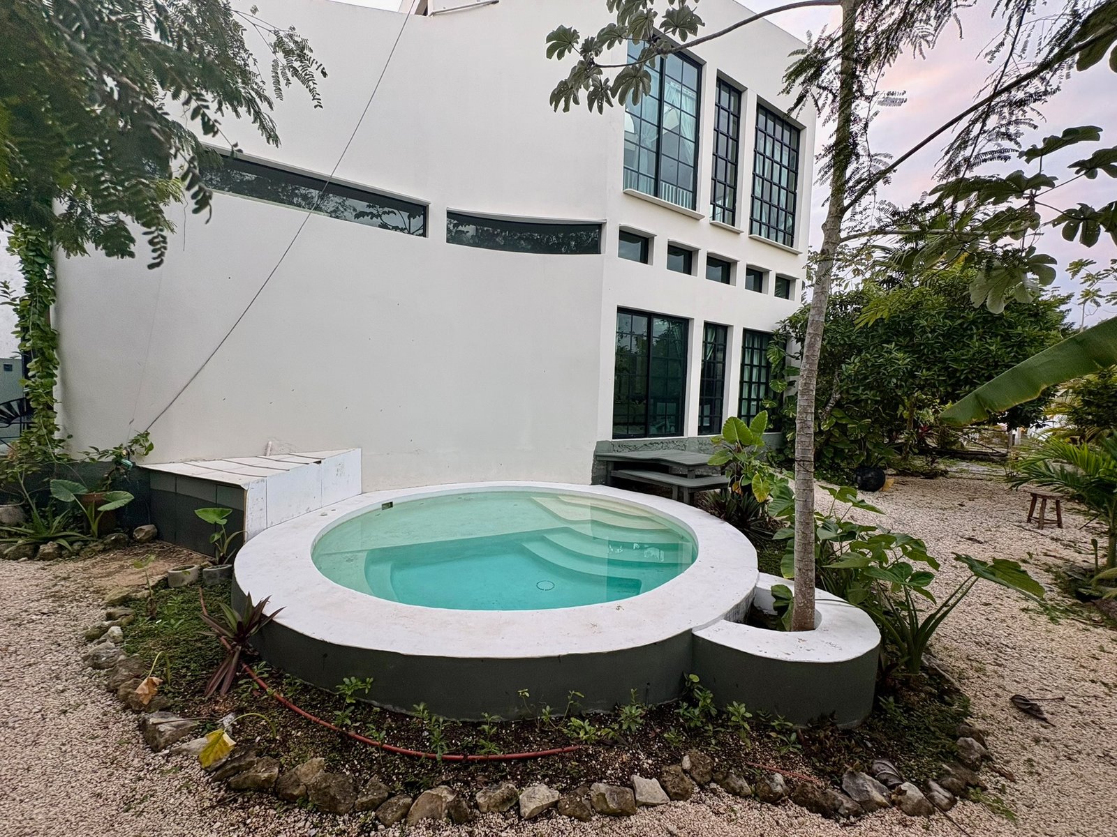 Casa Blanca, the two-story white house at Rancho Verde Tulum, with its round plunge pool at dusk
