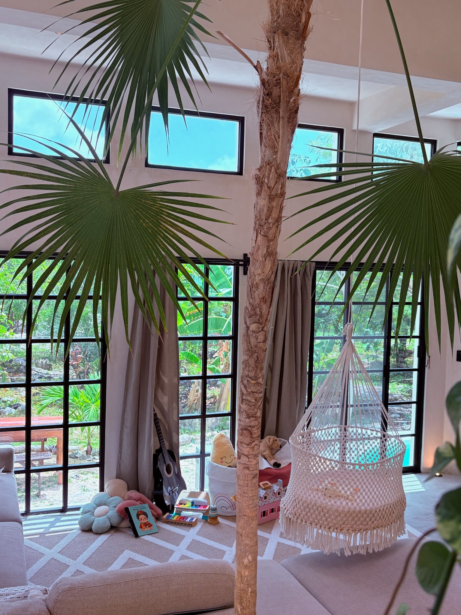 Casa Blanca living room with an indoor palm growing through the floor, a hanging cradle and full-height windows, Rancho Verde Tulum, Tulum, Mexico