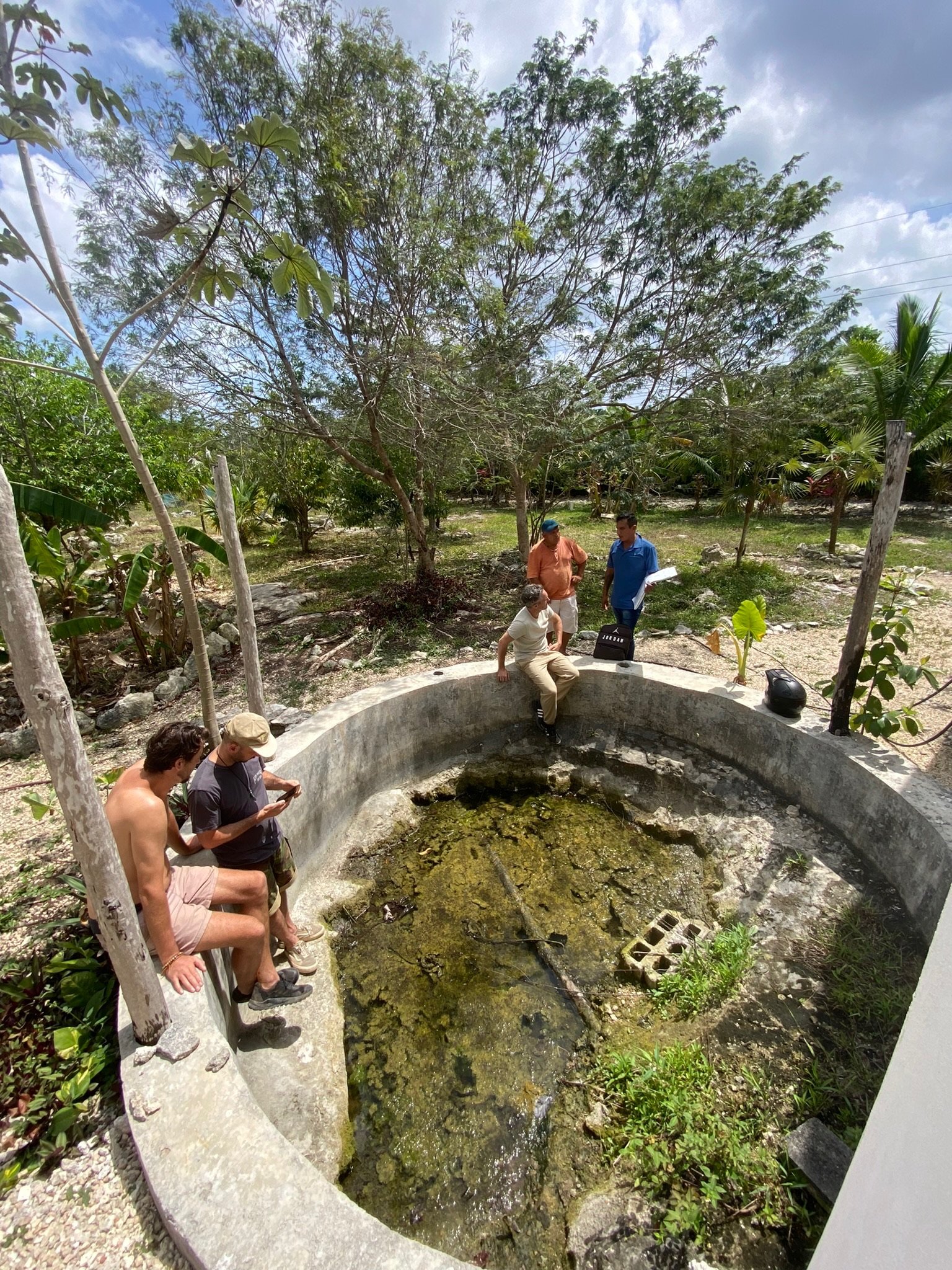 Unfinished round concrete pool shell with the team standing inside, Rancho Verde Tulum, Tulum, Mexico