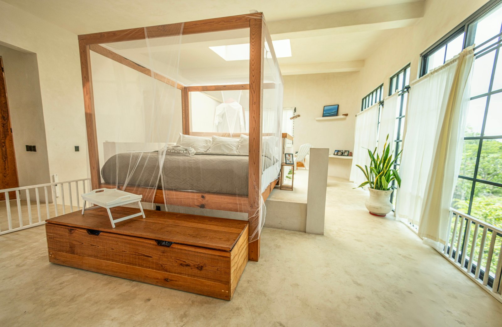 Hand-built wooden canopy bed and storage chest in a skylit bedroom, Rancho Verde Tulum, Tulum, Mexico