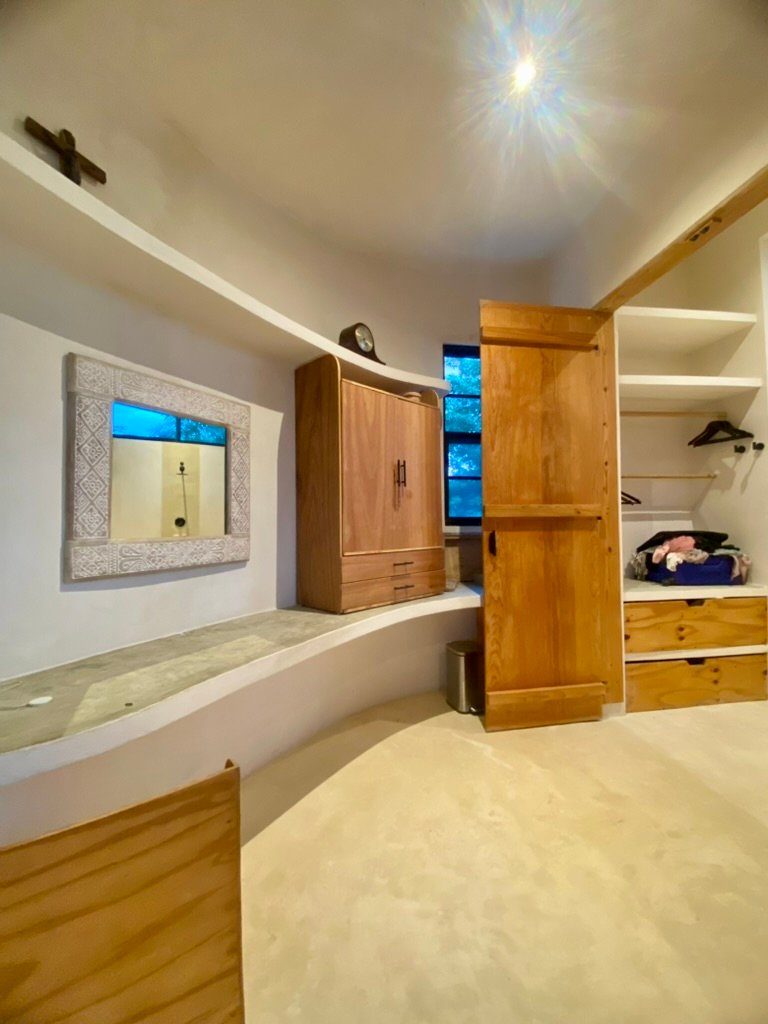 Hand-built wooden wardrobe doors and open shelving in a plastered bedroom, Rancho Verde Tulum, Tulum, Mexico