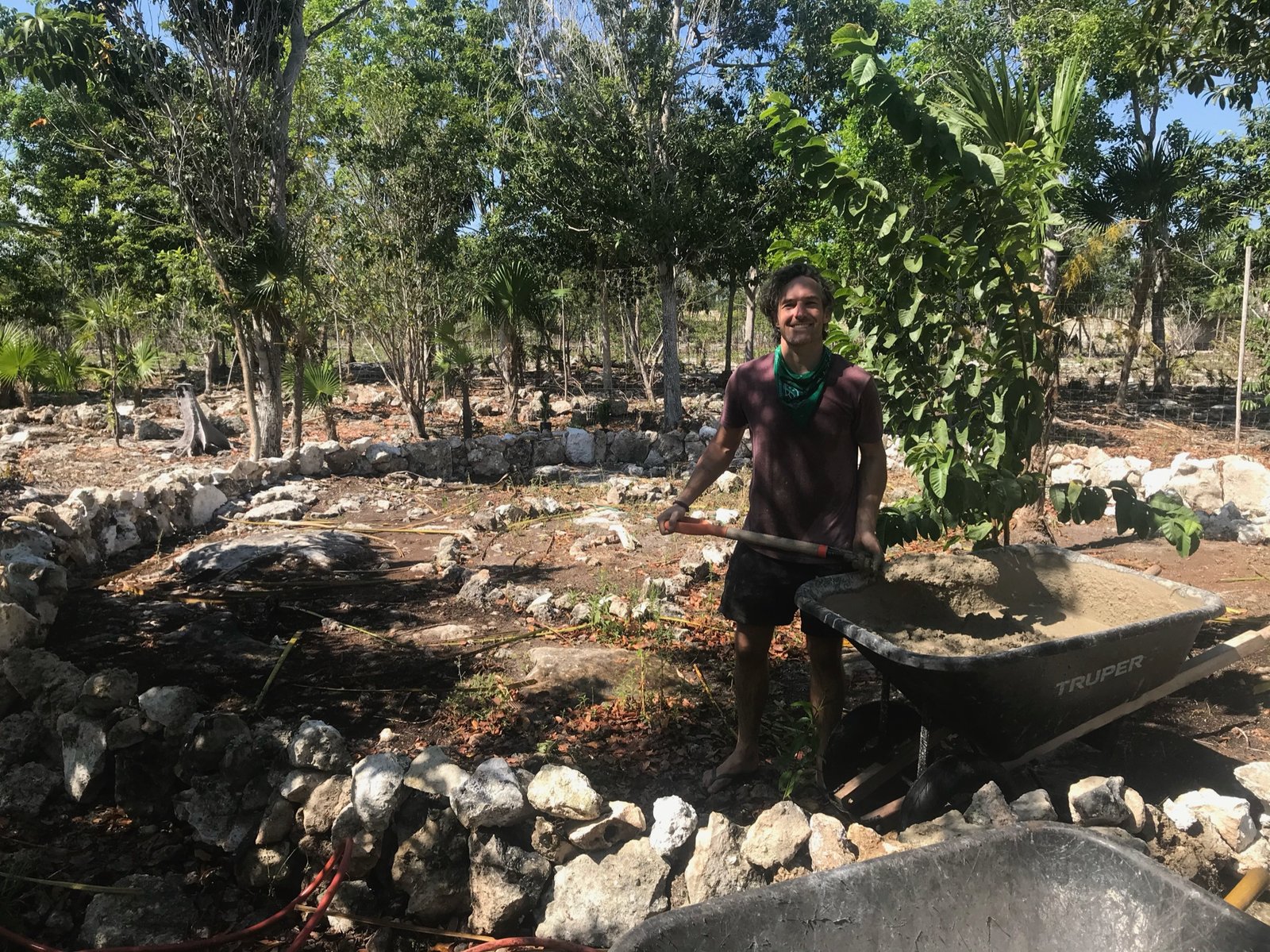 Founder Thomas with a wheelbarrow of concrete for the garden build, Rancho Verde Tulum, Tulum, Mexico