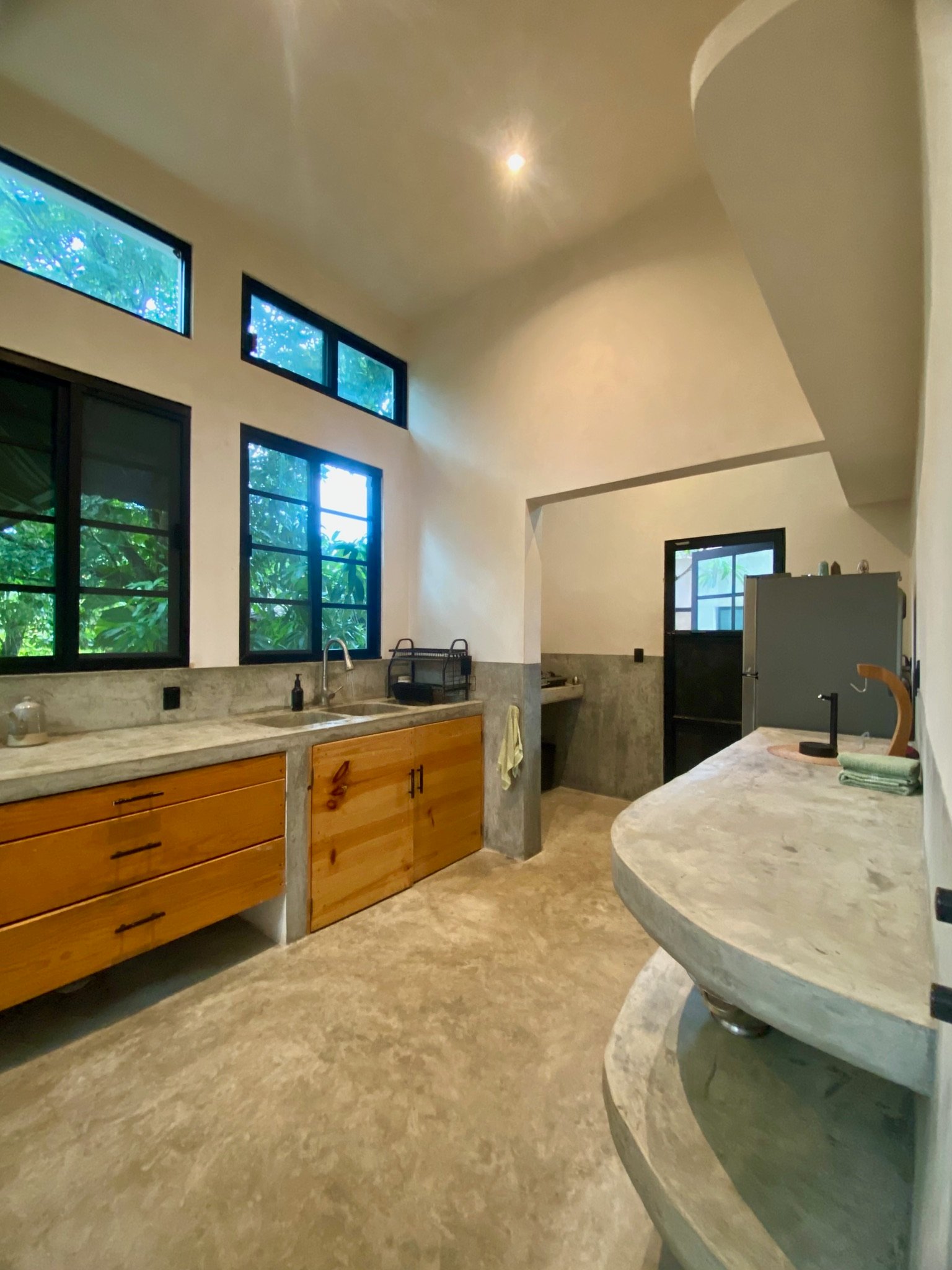 Concrete kitchen with poured counters, wooden cabinet fronts, double sink and jungle windows, Rancho Verde Tulum, Tulum, Mexico