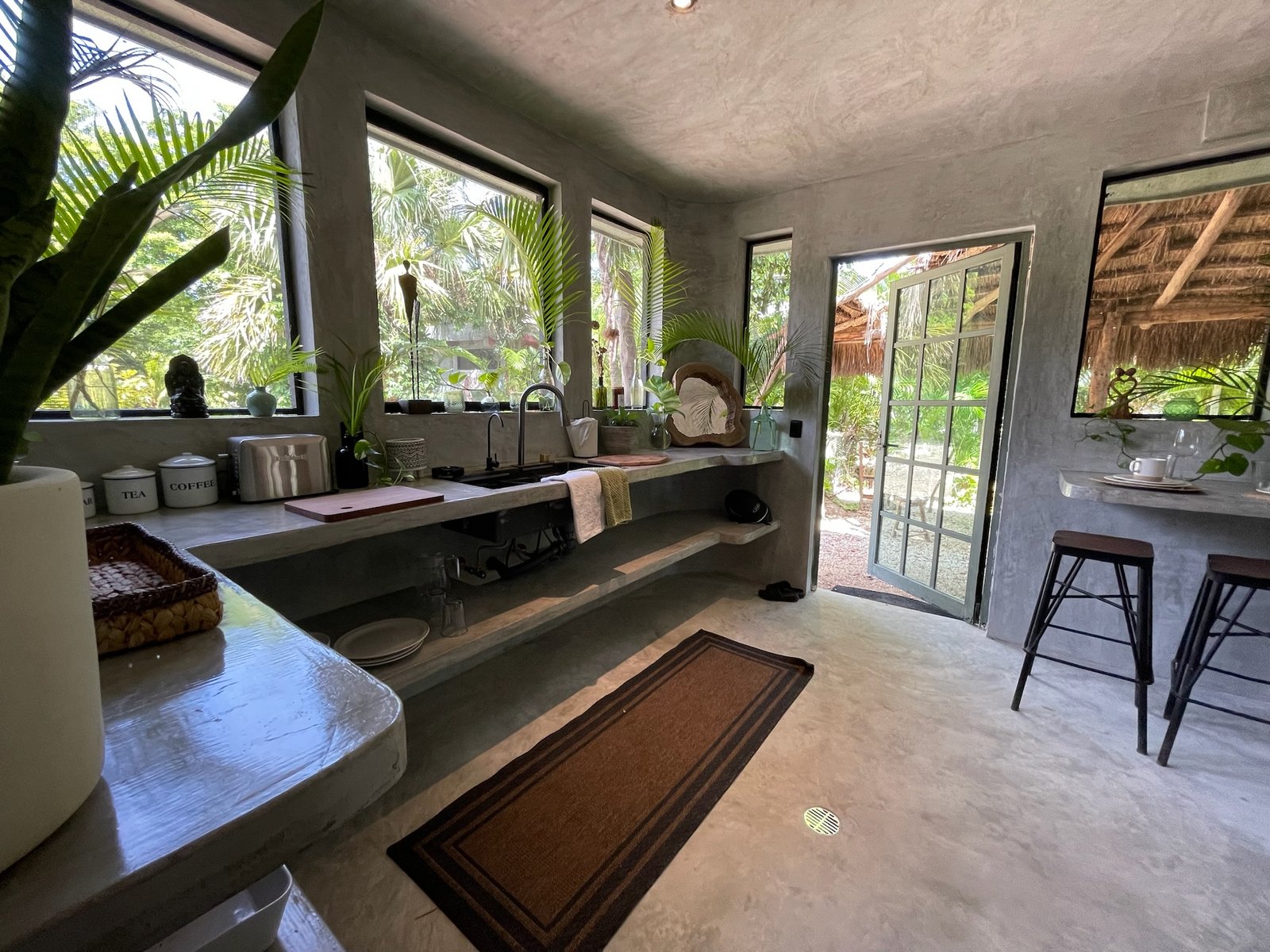 Concrete kitchen with open shelving and a view out to the palapa, Rancho Verde Tulum, Tulum, Mexico