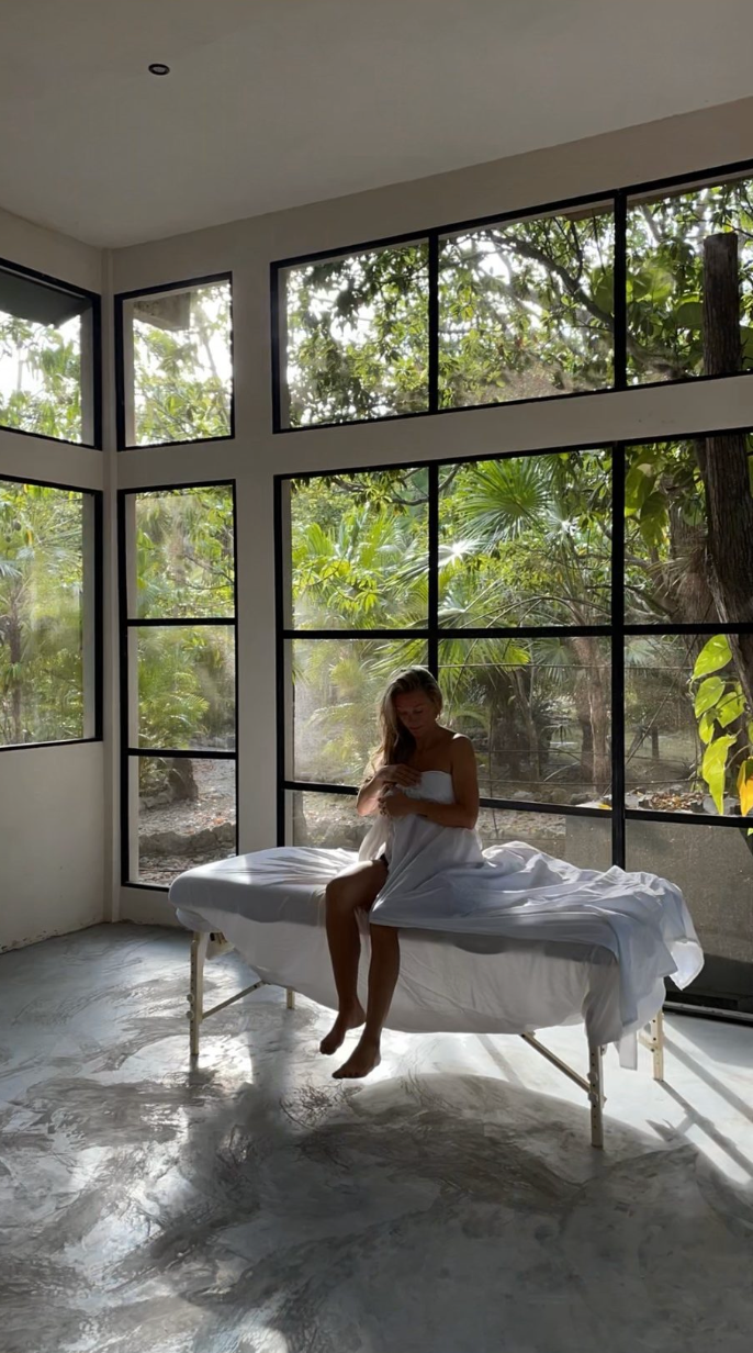 Finished massage room with a treatment table and floor-to-ceiling jungle windows, Rancho Verde Tulum, Tulum, Mexico