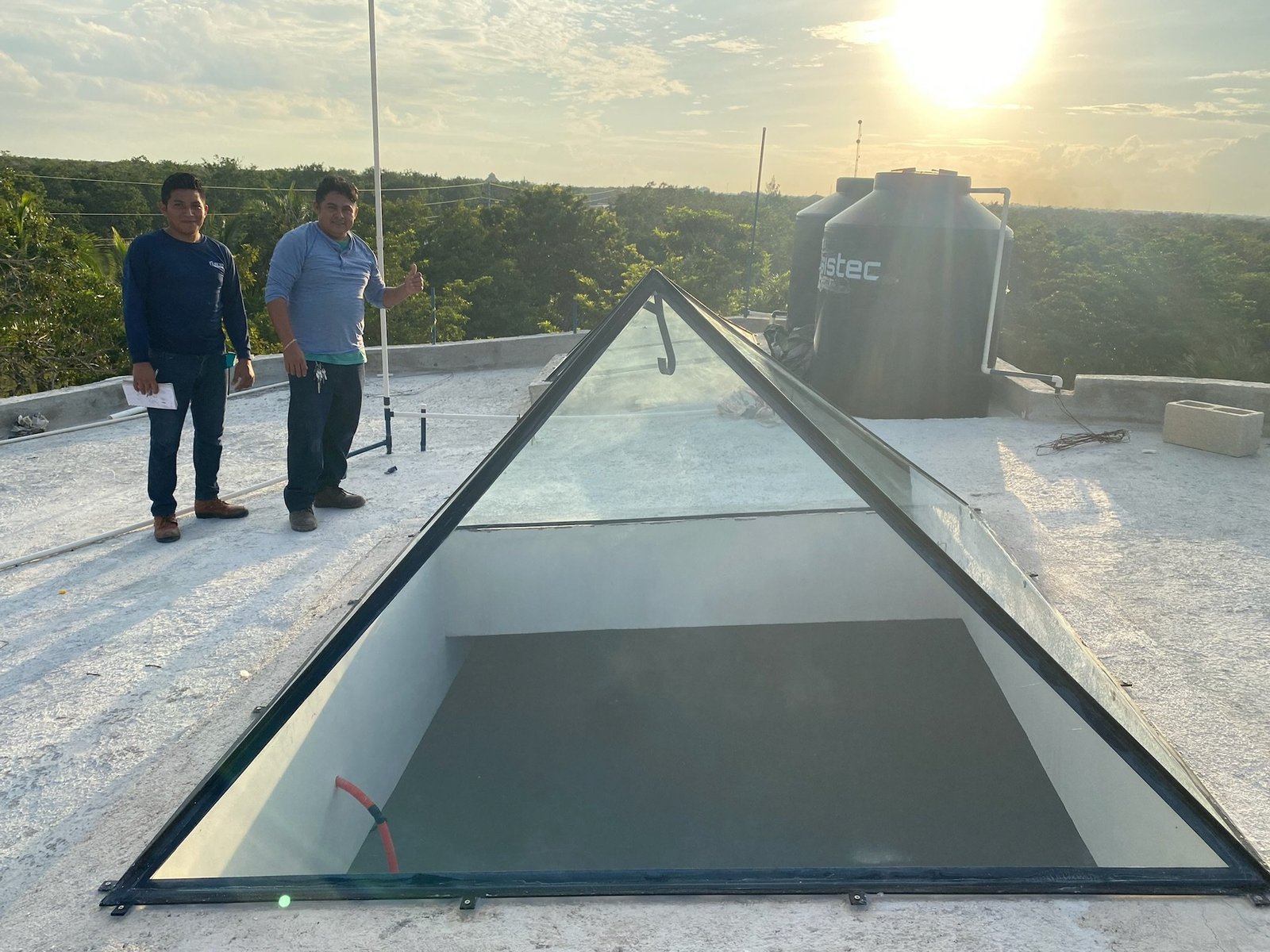 Two of the crew next to the finished glass pyramid roof window they installed, Rancho Verde Tulum, Tulum, Mexico