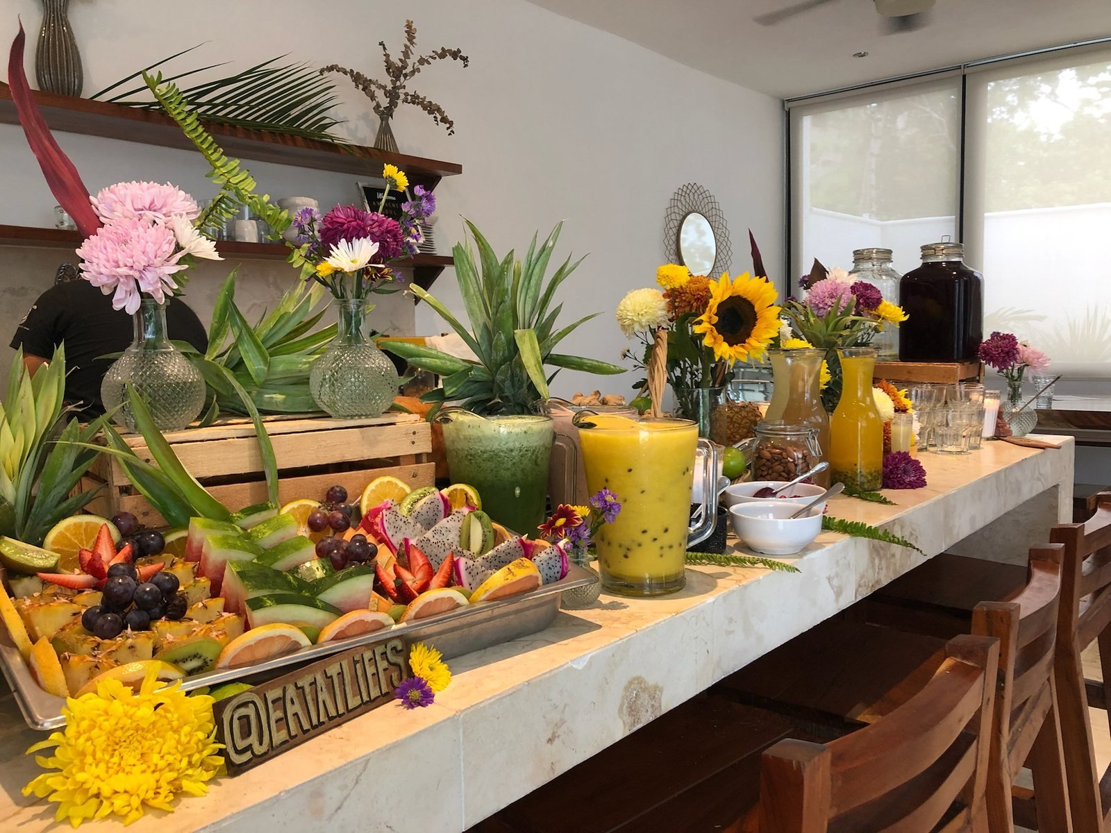 Retreat breakfast bar with a tropical fruit platter, fresh juices and flowers, vegan event catering by Liefs Tulum at Rancho Verde