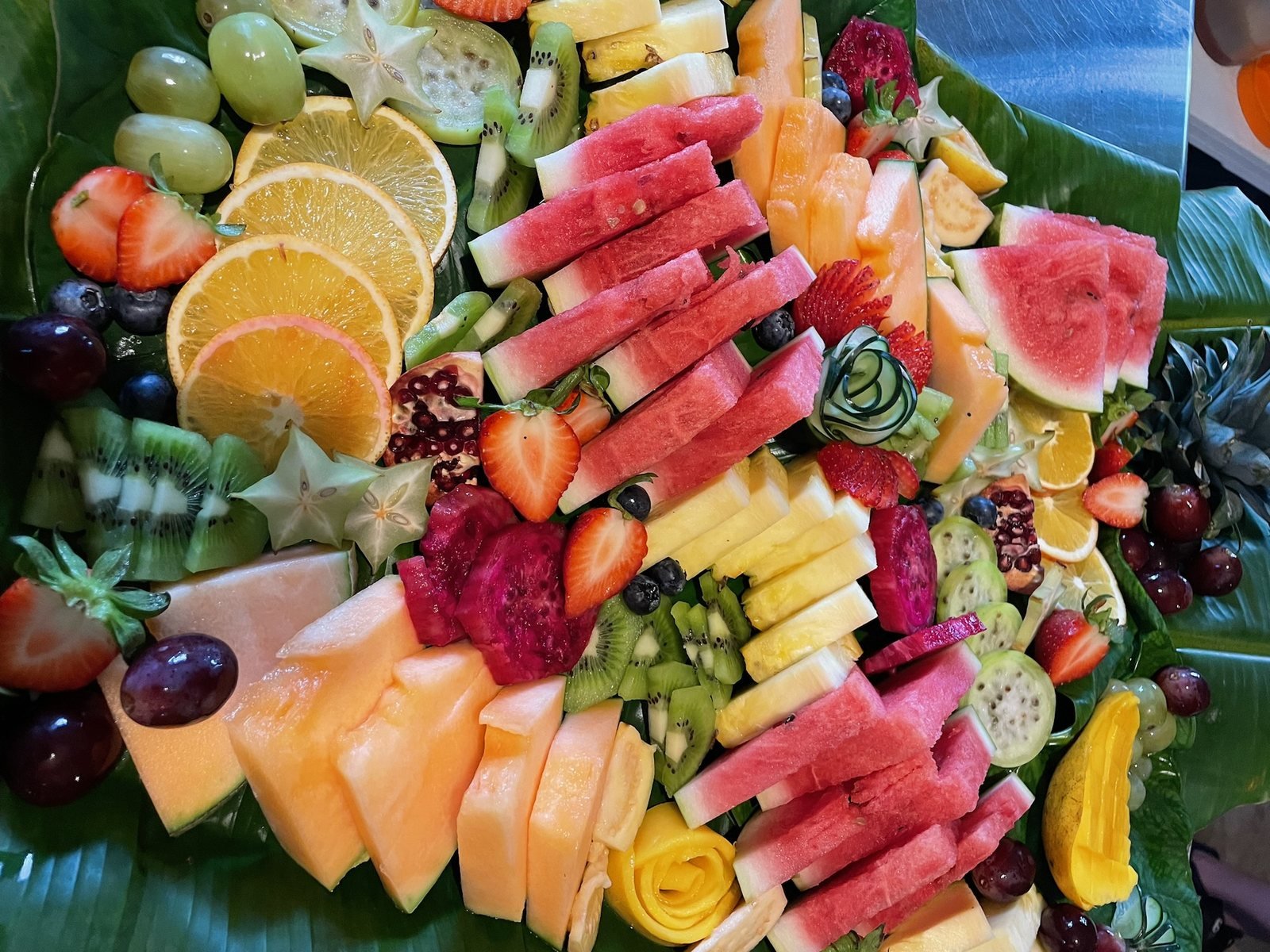 Tropical fruit platter on banana leaves with watermelon, star fruit, cactus fruit and pomegranate, vegan event catering by Liefs Tulum at Rancho Verde