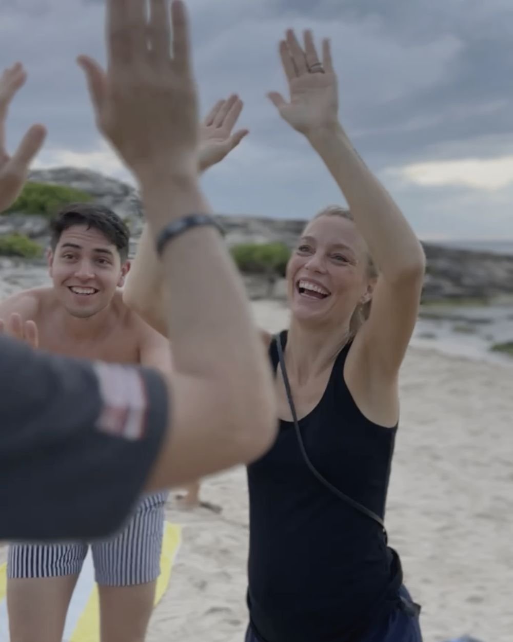 Retreat guests high-fiving and laughing on the beach in Tulum