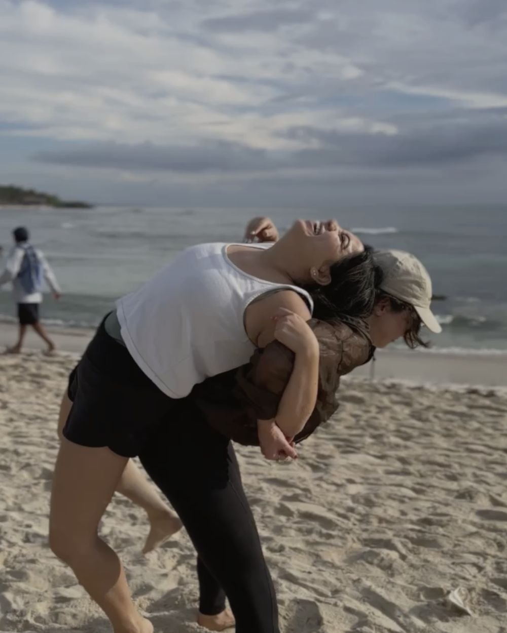 Two women laughing during a trust exercise on the beach in Tulum