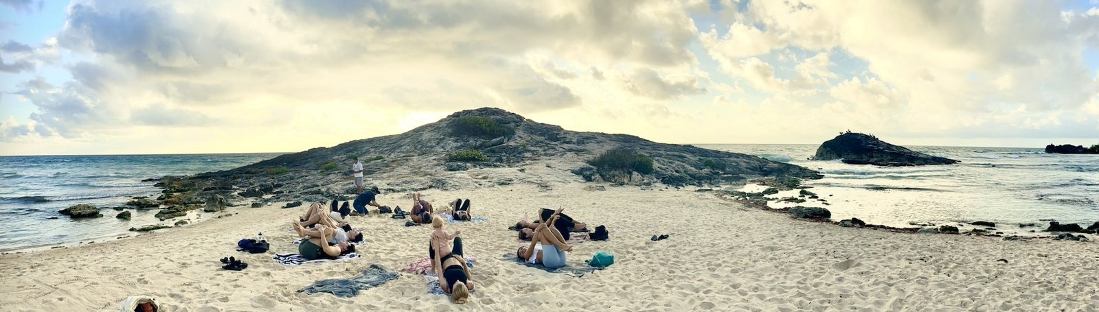 Sunrise beach yoga session on a rocky shoreline near Tulum during the Purpose Reset Retreat