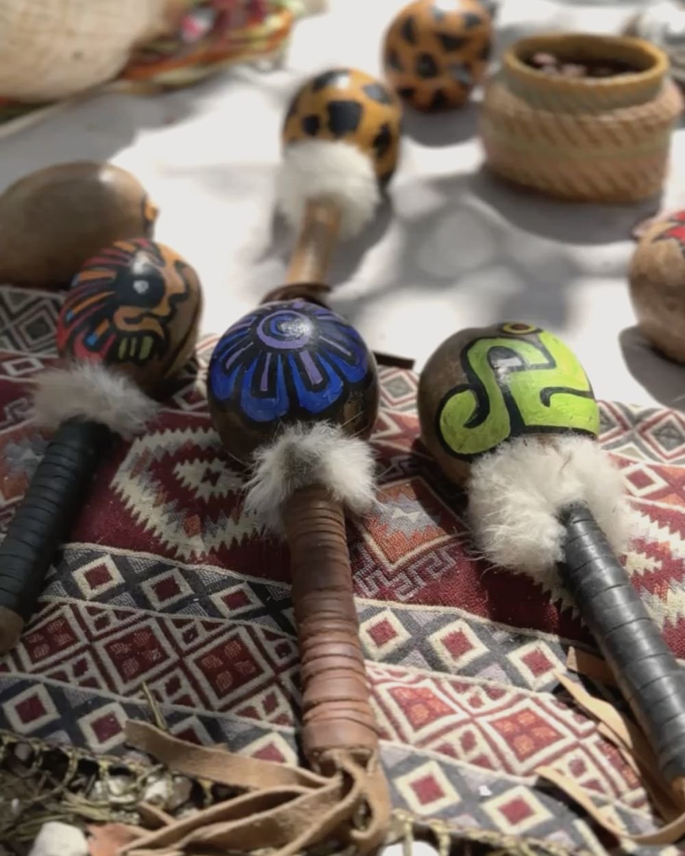 Hand-painted ceremonial rattles on a woven textile during a retreat ceremony in Tulum