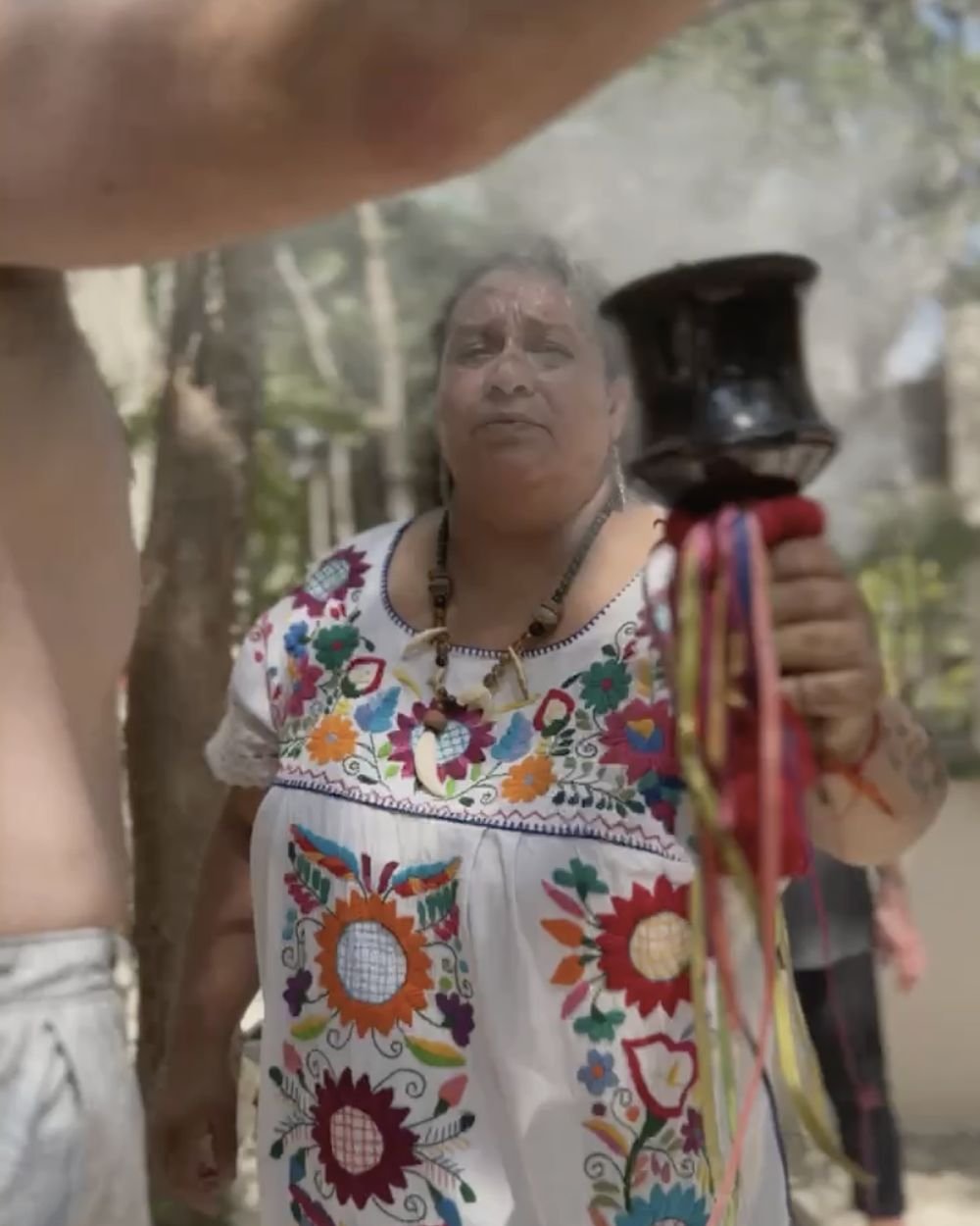 Local ceremony guide blessing guests with copal smoke at a Rancho Verde Tulum retreat