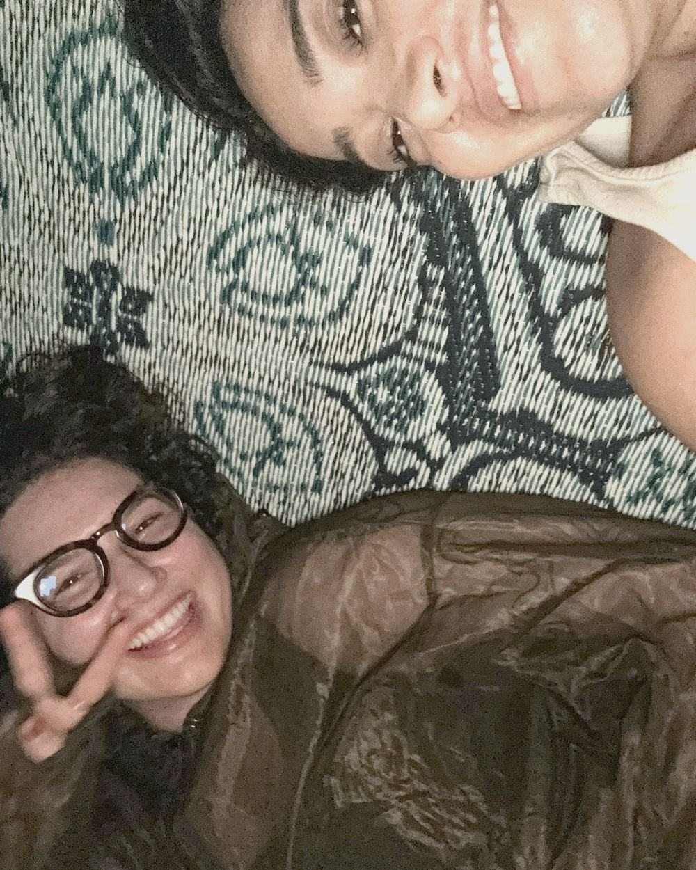 Two retreat guests laughing together on a rug after an evening session at Rancho Verde Tulum