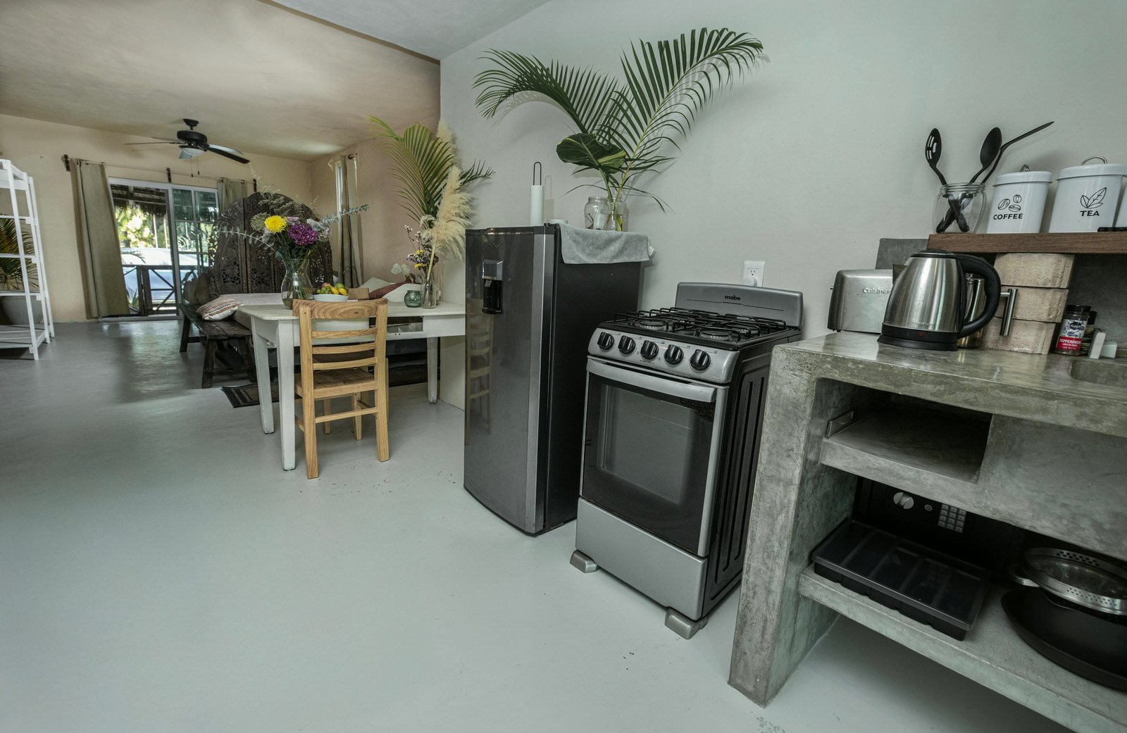 Kitchen with stove, fridge and concrete counters beside the dining table, The Chapel, Airbnb at Rancho Verde Tulum