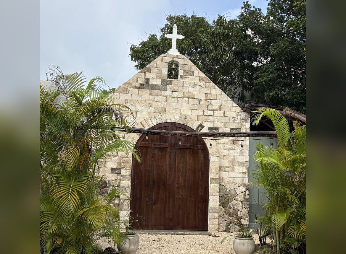 Stone facade with white cross and arched wooden doors, The Chapel, Airbnb at Rancho Verde Tulum