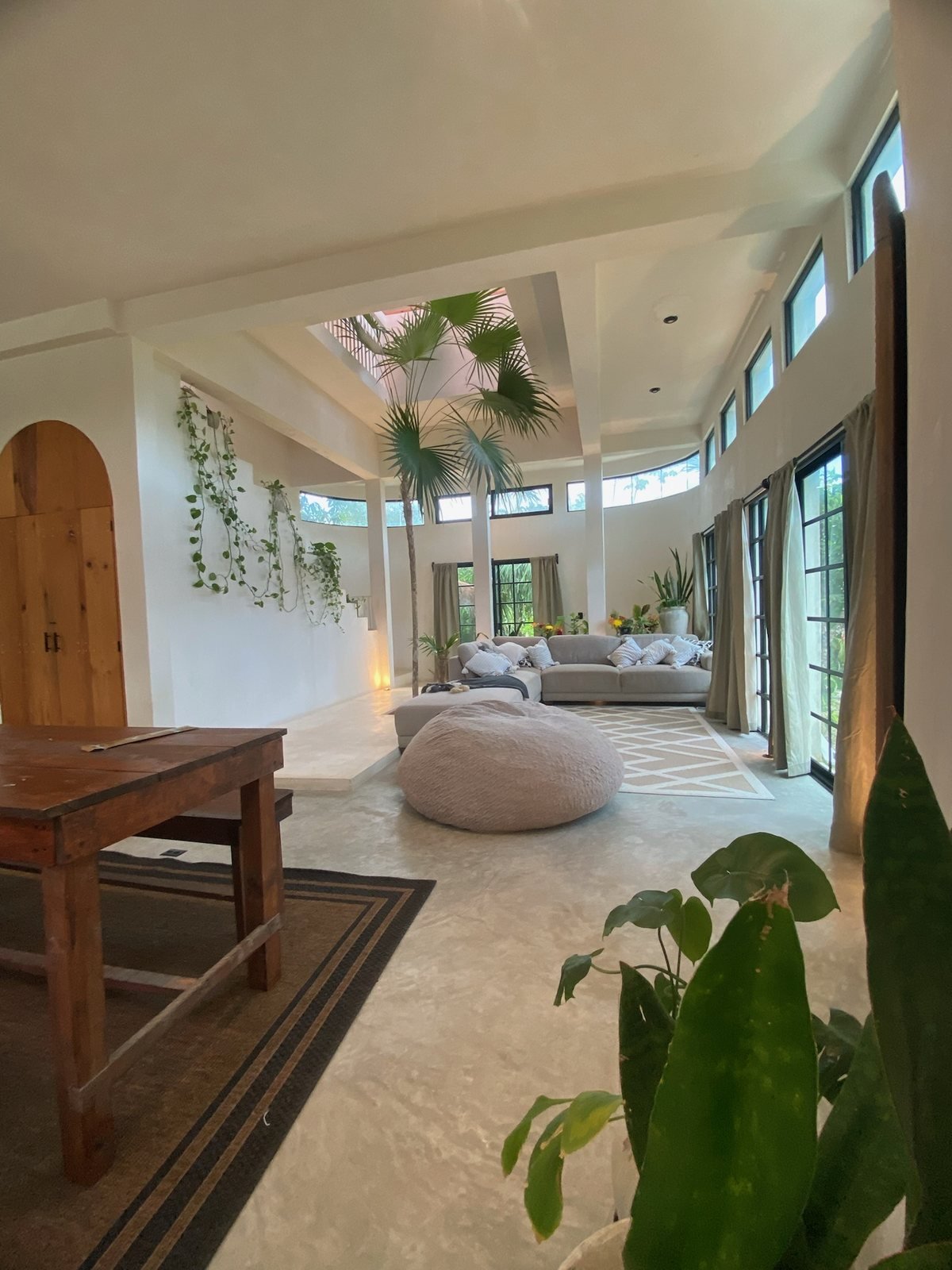 Double-height living room with sectional sofa and an indoor palm under the skylight, The Villa, Airbnb at Rancho Verde Tulum