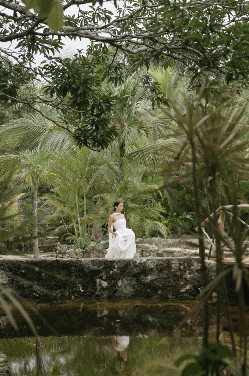 Bride in a strapless gown reflected in the jungle pond at Rancho Verde Tulum