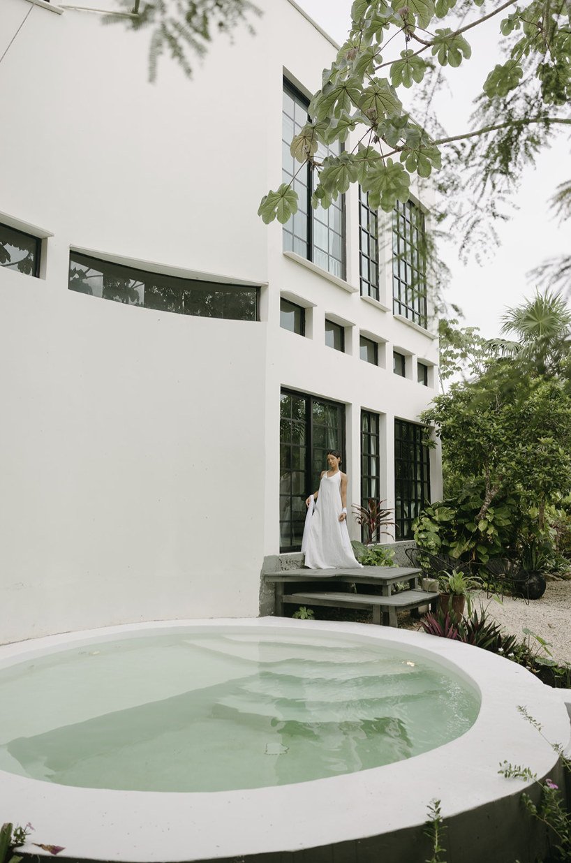 Bride in a white dress beside the round plunge pool of the white villa at Rancho Verde Tulum