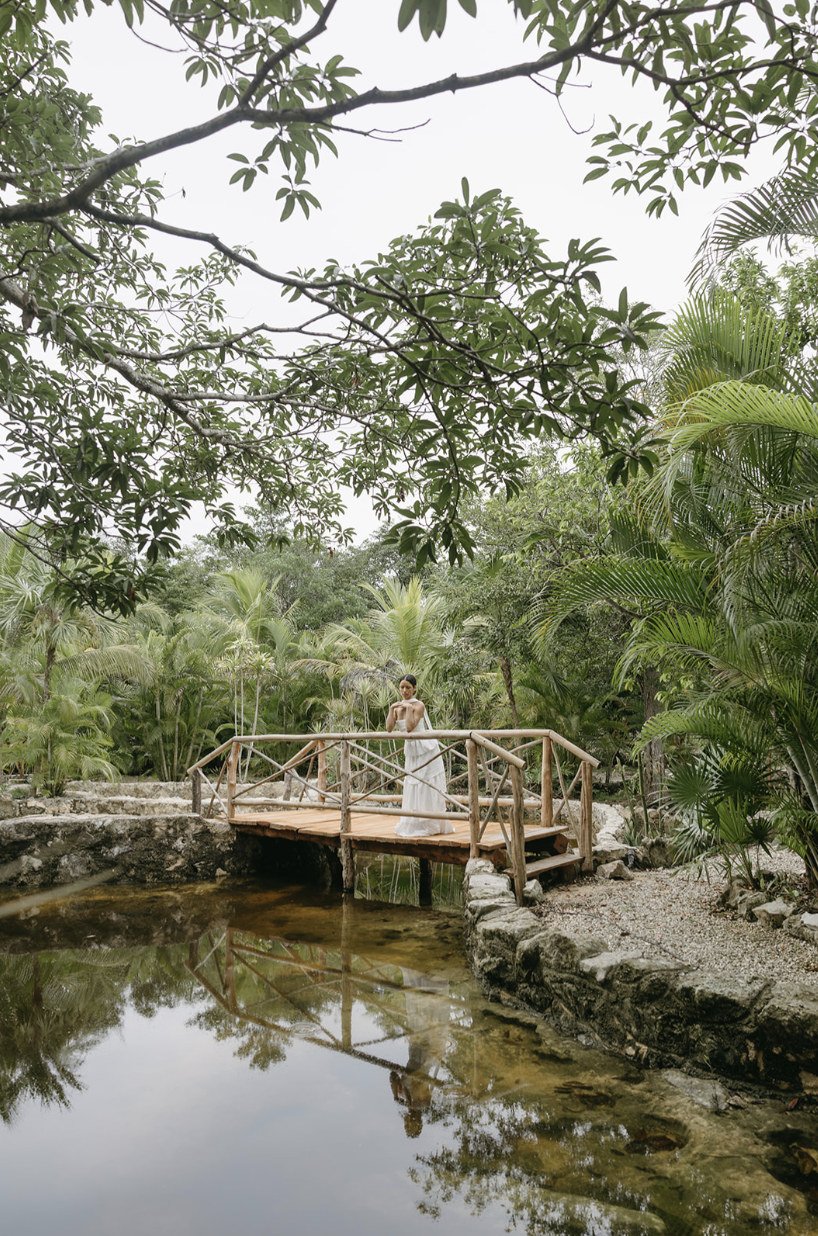 Bride on the wooden bridge over the jungle pond at Rancho Verde Tulum