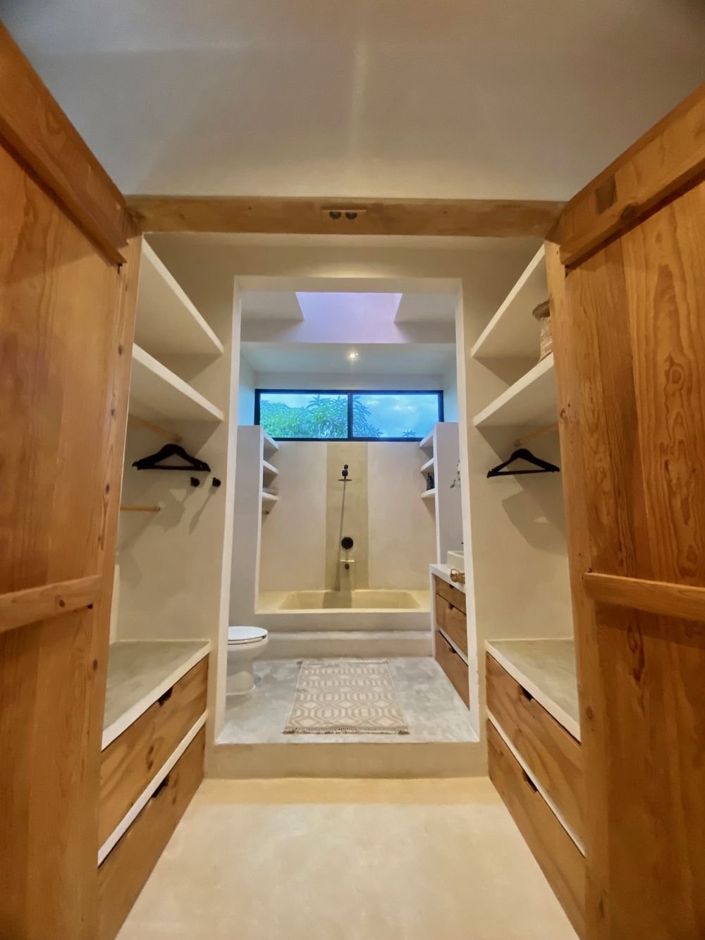 Spacious walk-in closet leading to a symmetrical bathroom with skylight and walk-in shower in Casa Blanca, a wedding suite at Rancho Verde Tulum