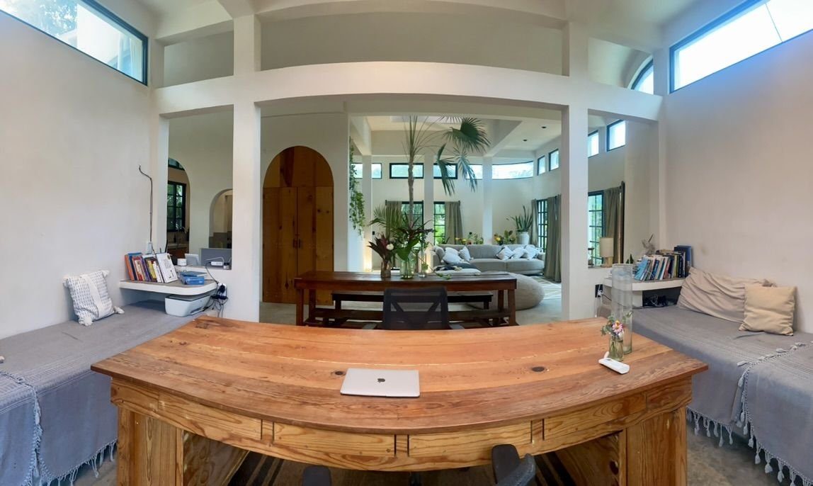 Light-filled Casa Blanca living room with a long wooden dining table and arched doors at Rancho Verde Tulum