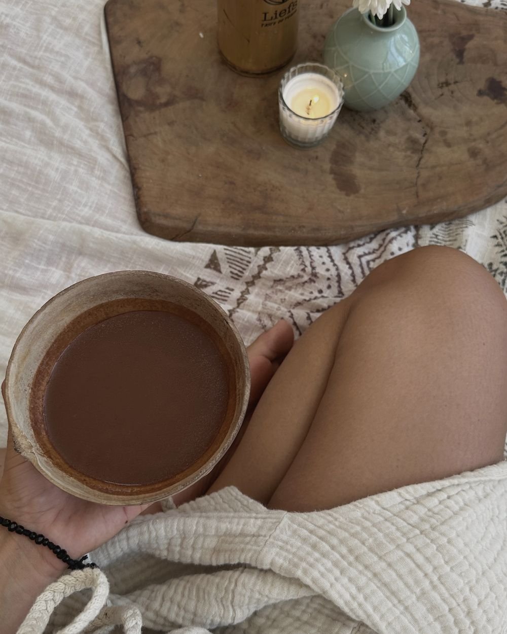 Bowl of ceremonial cacao with a candle and a Liefs bottle at Rancho Verde Tulum
