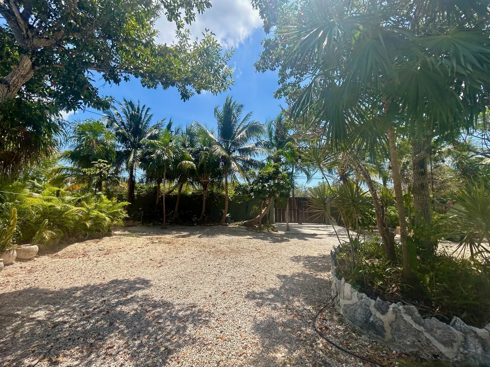 Gated gravel courtyard framed by palms, Rancho Verde Tulum retreat sanctuary, Tulum Mexico
