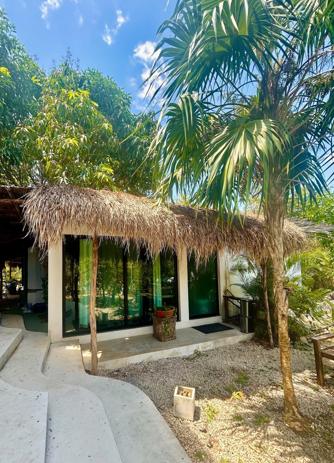 Palapa-roofed guest house under palms and mango trees, Rancho Verde Tulum retreat sanctuary, Tulum Mexico