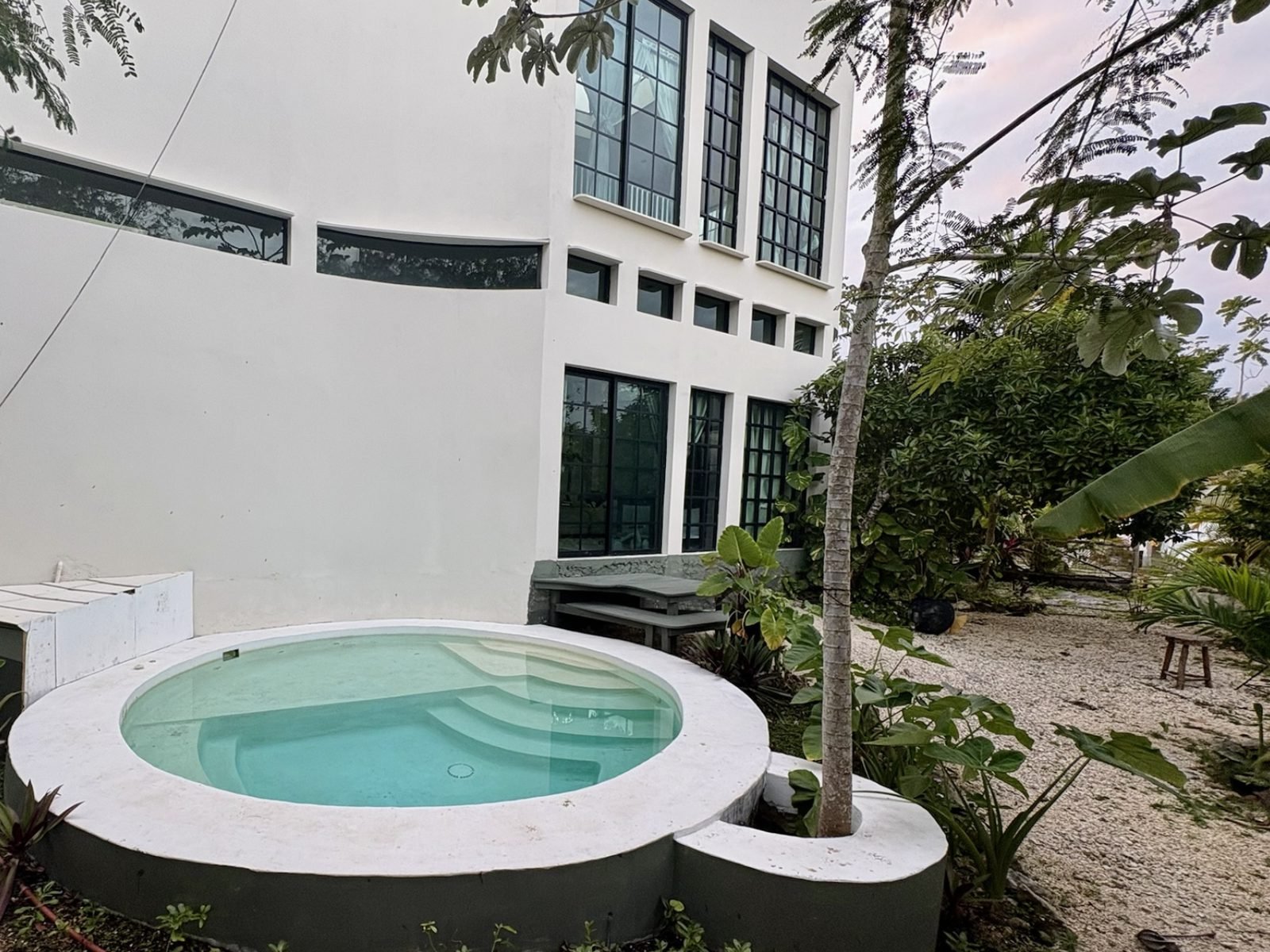 White villa with a round plunge pool and tropical garden at Rancho Verde Tulum retreat sanctuary, Tulum Mexico
