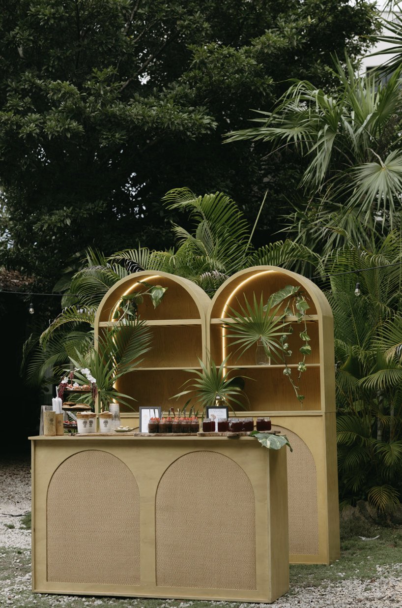 Wooden dessert bar with lit arched cabinets in the garden at Rancho Verde Tulum