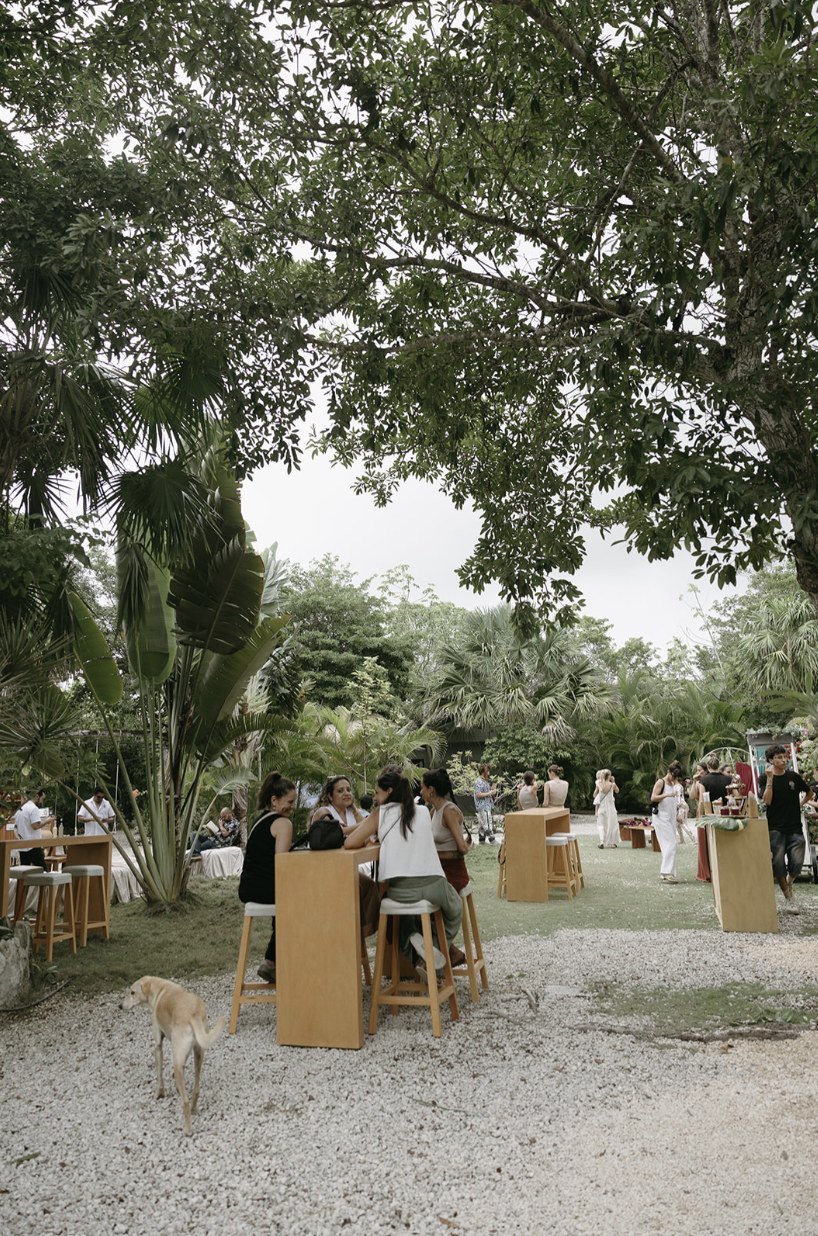 Guests at wooden high tables under the big trees during a celebration at Rancho Verde Tulum