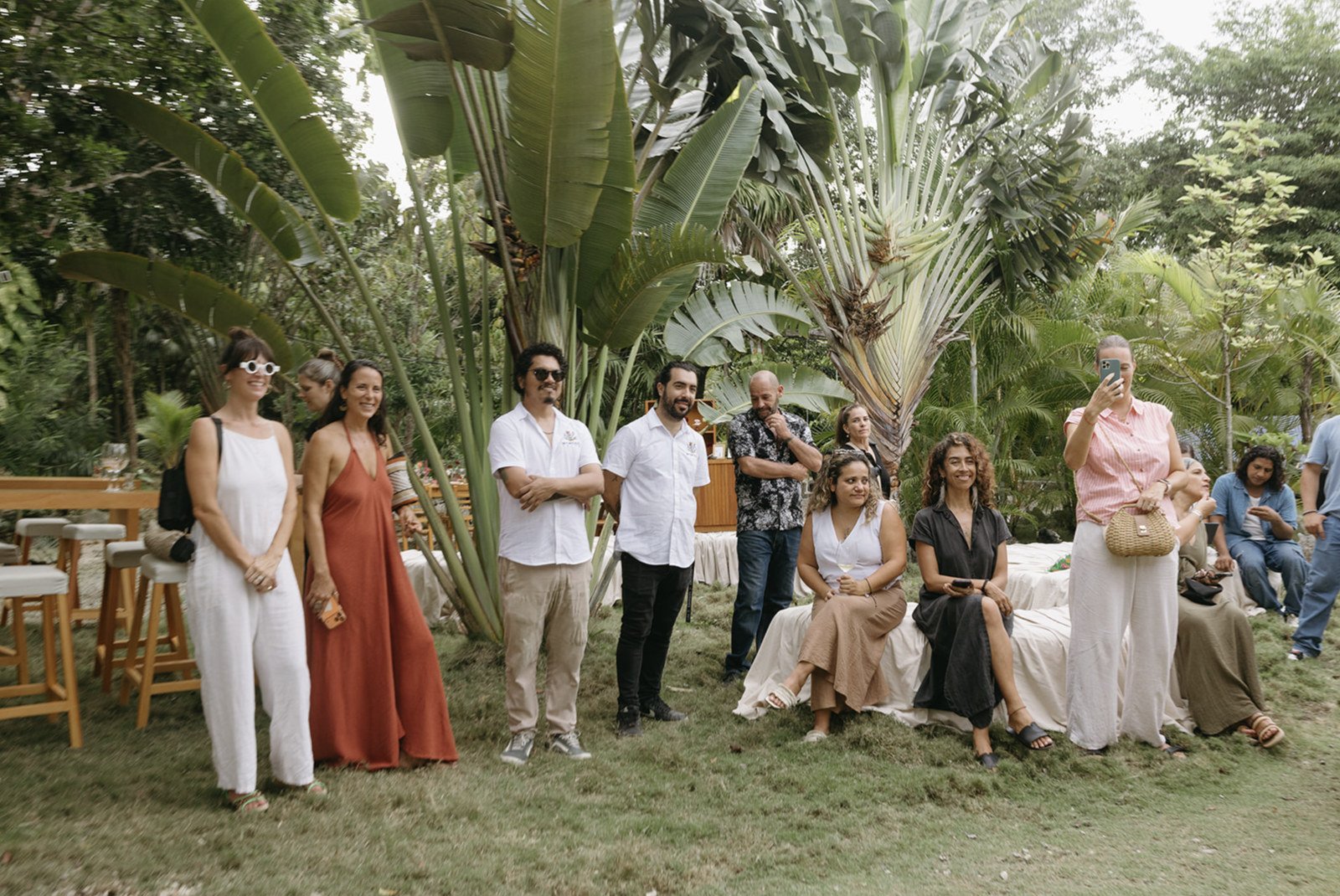 Wedding guests gathered under traveler's palms on the lawn at Rancho Verde Tulum